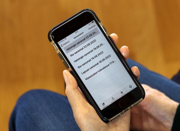 Kännykän ruudulla luettelo, jossa sanomalehtien nimiä.